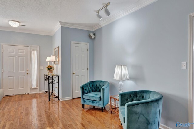 sitting room with a textured ceiling, hardwood / wood-style flooring, track lighting, and ornamental molding