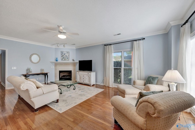 living room featuring a textured ceiling, light hardwood / wood-style flooring, ceiling fan, and crown molding