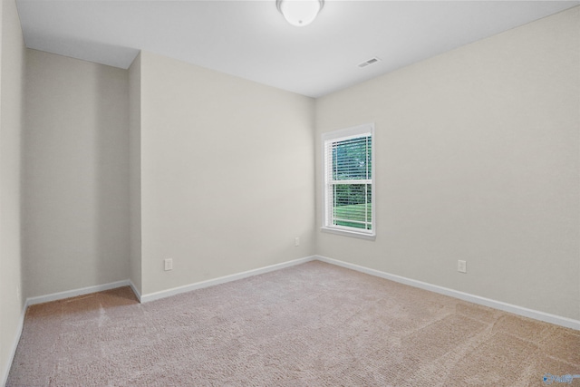 empty room with carpet, visible vents, and baseboards