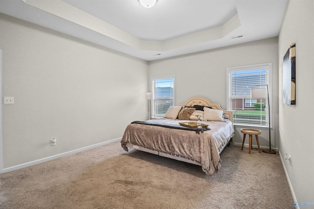 bedroom featuring carpet, visible vents, a tray ceiling, and baseboards