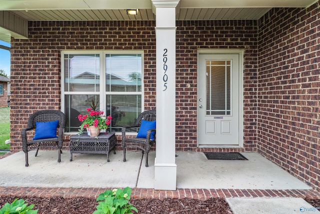 entrance to property with a porch and brick siding