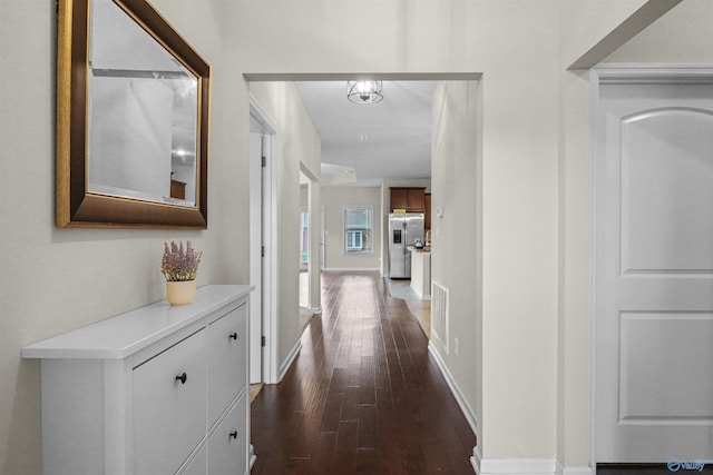 hall with visible vents, baseboards, and dark wood finished floors