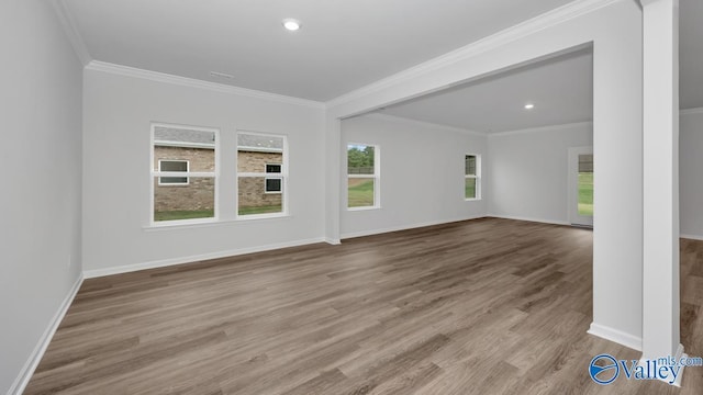 unfurnished room featuring wood finished floors, crown molding, and a healthy amount of sunlight