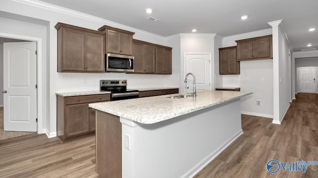 kitchen featuring a sink, stainless steel appliances, ornamental molding, and light wood finished floors