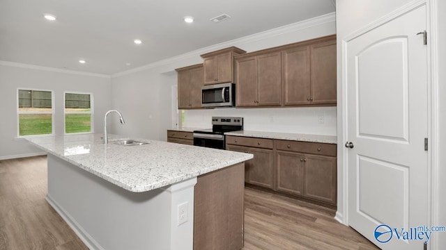 kitchen featuring visible vents, light wood-type flooring, a sink, appliances with stainless steel finishes, and crown molding