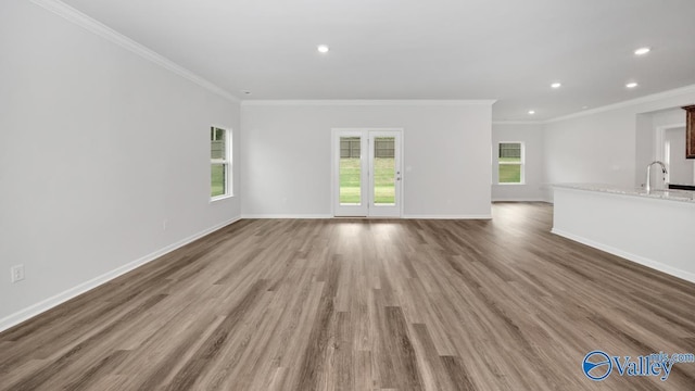 unfurnished living room with crown molding, recessed lighting, wood finished floors, and baseboards