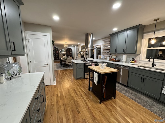 kitchen with sink, island exhaust hood, decorative light fixtures, a kitchen island, and appliances with stainless steel finishes