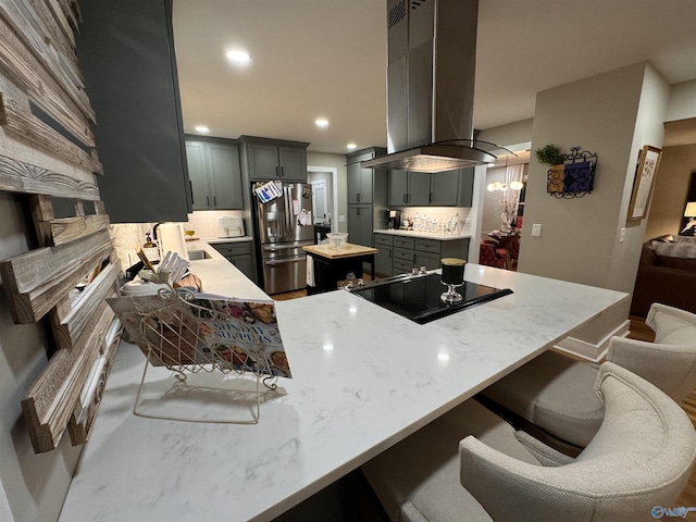 kitchen featuring stainless steel fridge with ice dispenser, backsplash, kitchen peninsula, island range hood, and black electric stovetop