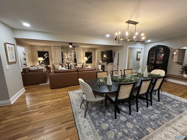 dining room with ceiling fan with notable chandelier and hardwood / wood-style flooring