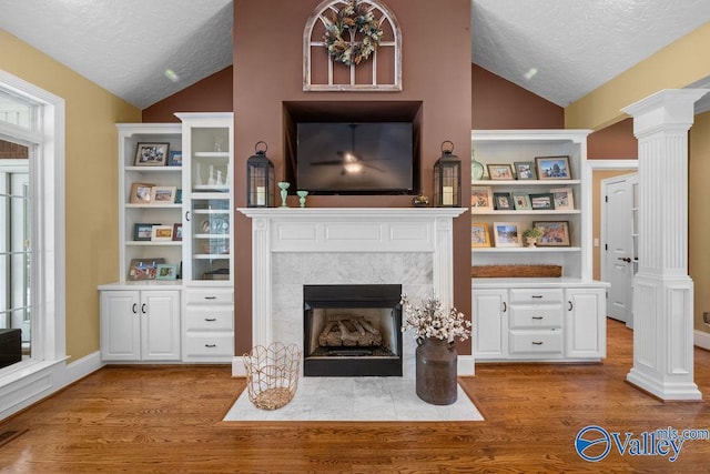 219 Sharp Dr, Gadsden, AL 35903 - living area with lofted ceiling, a tile fireplace, a textured ceiling, wood finished floors, and ornate columns