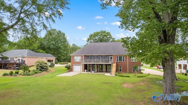 219 Sharp Dr, Gadsden, AL 35903 - back of property featuring concrete driveway, a garage, a wooden deck, and a yard