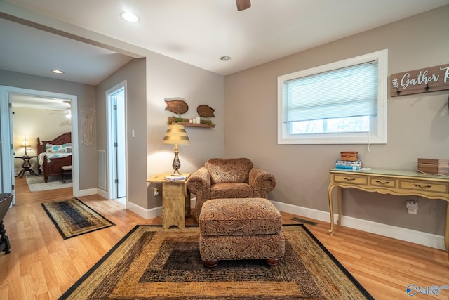 sitting room with baseboards, ceiling fan, visible vents, and light wood finished floors