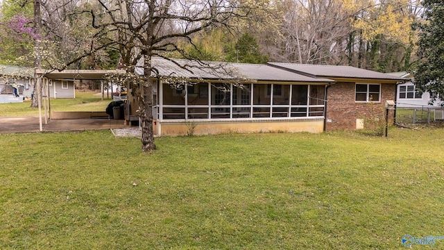 ranch-style house featuring a sunroom, brick siding, a front yard, and a carport