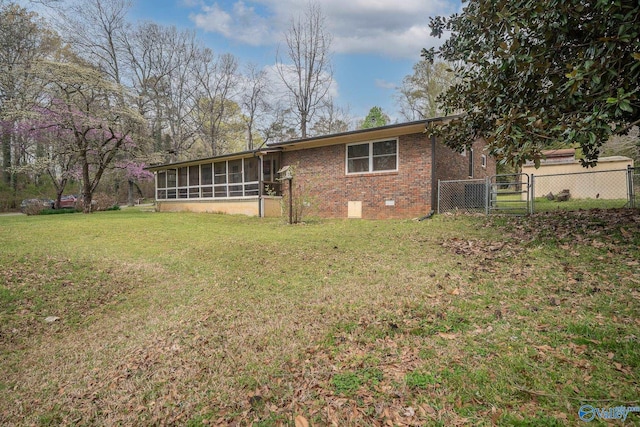 back of property with a sunroom, fence, a gate, brick siding, and a yard