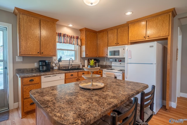 kitchen featuring a sink, dark countertops, brown cabinets, and white appliances