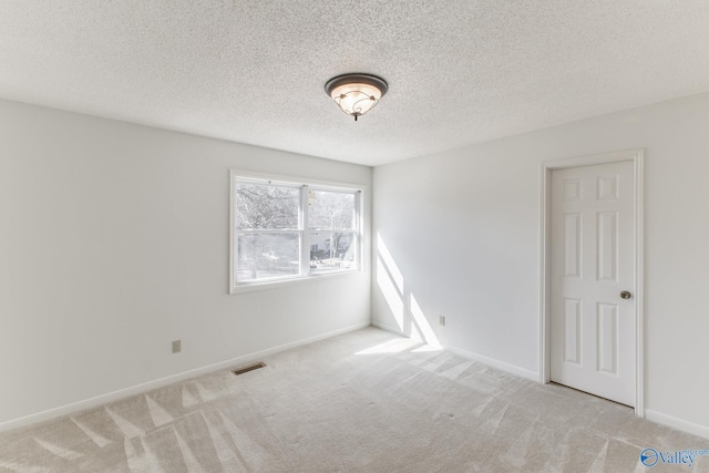 empty room featuring visible vents, baseboards, a textured ceiling, and carpet flooring