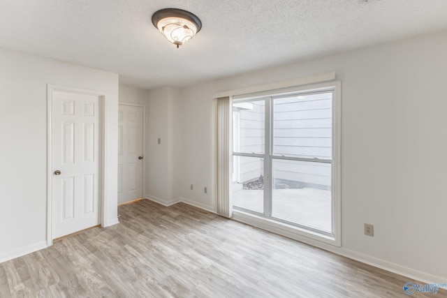 interior space with light wood-style flooring, baseboards, and a textured ceiling