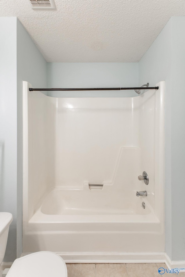 bathroom featuring visible vents, toilet, shower / washtub combination, and a textured ceiling