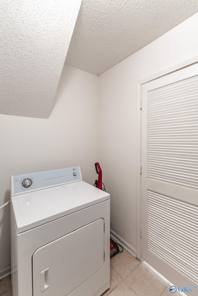 clothes washing area featuring a textured ceiling, washer / dryer, light tile patterned floors, and laundry area