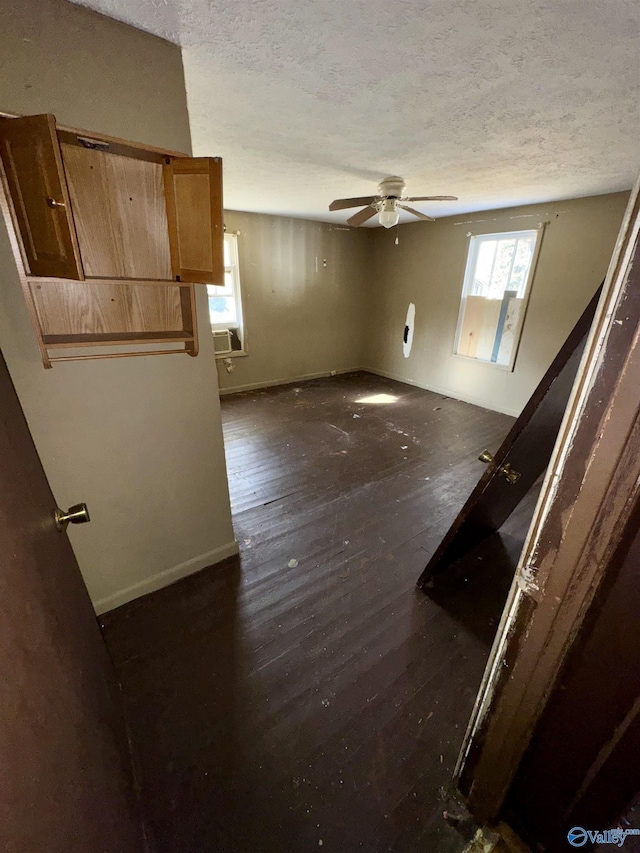 empty room featuring dark wood-type flooring, ceiling fan, and a textured ceiling