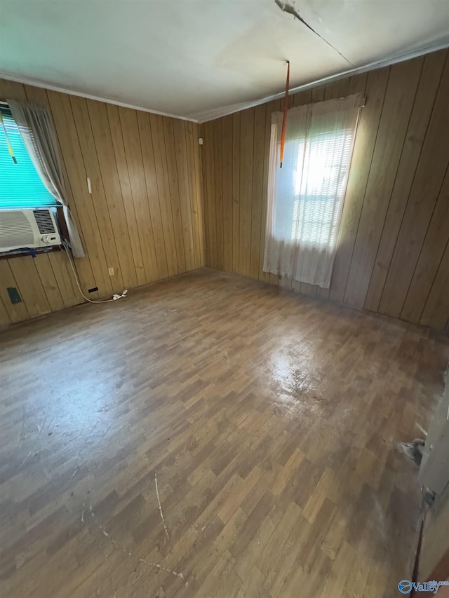 empty room featuring cooling unit, hardwood / wood-style flooring, and wood walls