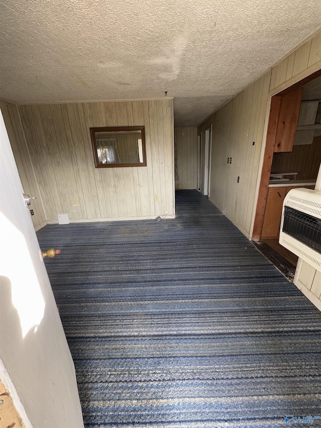 interior space featuring carpet flooring, heating unit, and a textured ceiling