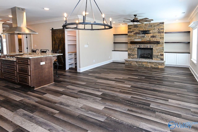 kitchen featuring decorative light fixtures, island exhaust hood, a barn door, open floor plan, and a kitchen island with sink