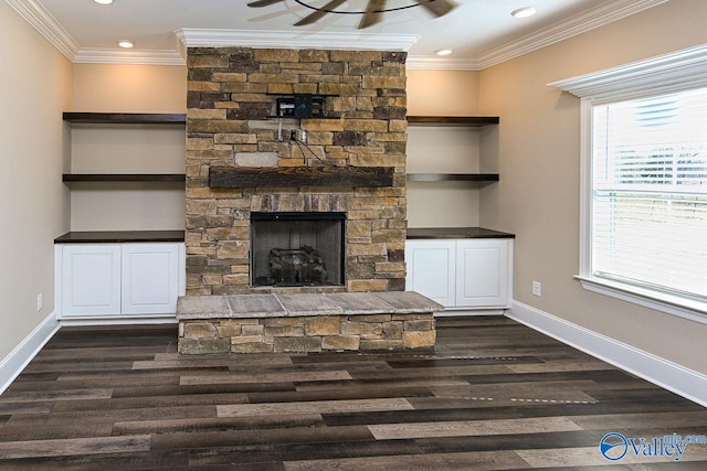 unfurnished living room featuring baseboards, a stone fireplace, dark wood finished floors, and crown molding