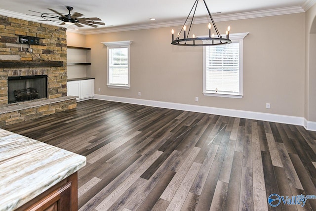 interior space with baseboards, ornamental molding, dark wood-style flooring, and a stone fireplace