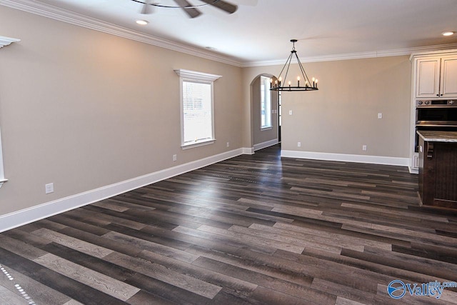 unfurnished dining area featuring arched walkways, an inviting chandelier, ornamental molding, dark wood-type flooring, and baseboards