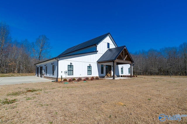 modern farmhouse featuring metal roof, board and batten siding, and a front yard