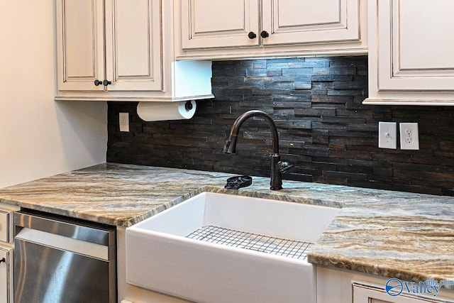 kitchen featuring light stone countertops, stainless steel dishwasher, decorative backsplash, and a sink