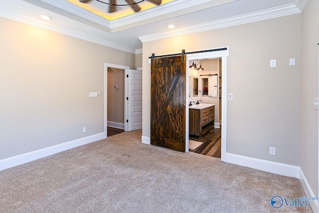 unfurnished bedroom with ornamental molding, carpet floors, baseboards, and a barn door