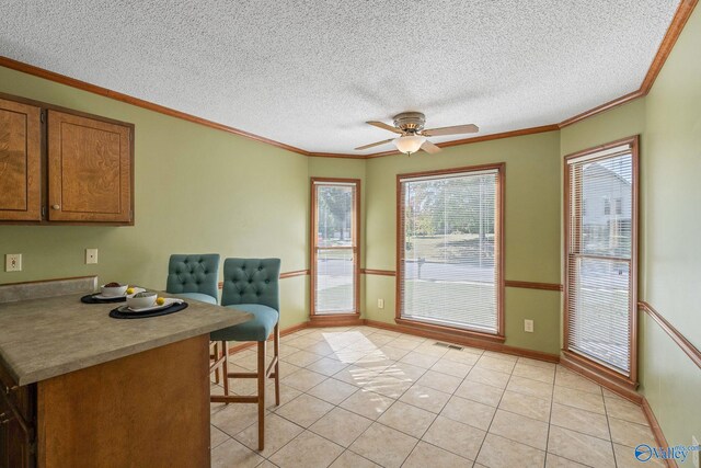 interior space featuring ornamental molding, light tile patterned flooring, a textured ceiling, and ceiling fan