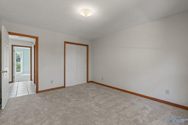 unfurnished bedroom featuring a closet, a textured ceiling, and light colored carpet