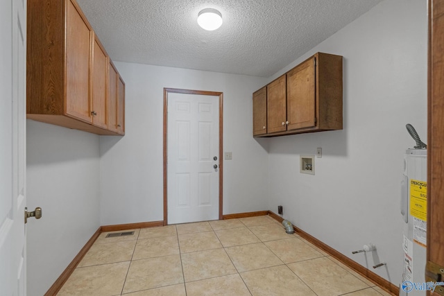 washroom featuring hookup for an electric dryer, light tile patterned flooring, a textured ceiling, electric water heater, and cabinets