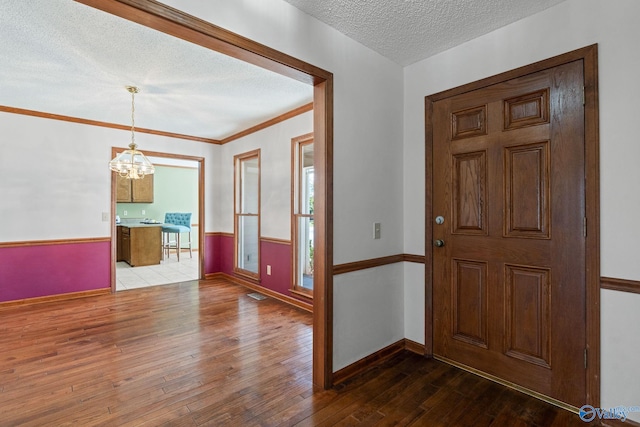 entrance foyer featuring a notable chandelier, hardwood / wood-style floors, a textured ceiling, and crown molding