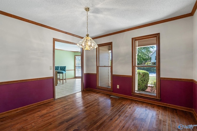 unfurnished dining area featuring a textured ceiling, crown molding, wood-type flooring, and an inviting chandelier