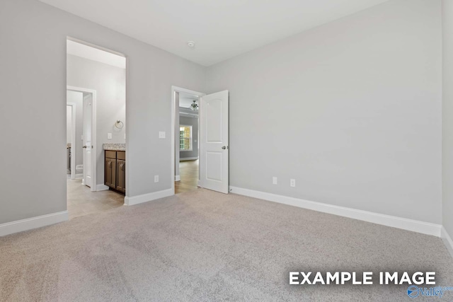 unfurnished bedroom featuring ensuite bath and light colored carpet