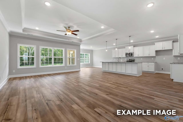 unfurnished living room featuring hardwood / wood-style floors, crown molding, and a tray ceiling