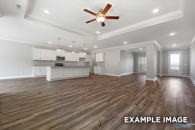 unfurnished living room featuring a raised ceiling, ceiling fan, dark wood-type flooring, and ornamental molding