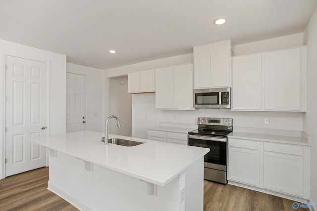 kitchen with a kitchen island with sink, sink, dark hardwood / wood-style flooring, white cabinetry, and stainless steel appliances