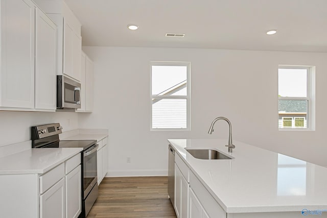 kitchen with white cabinets, stainless steel appliances, hardwood / wood-style flooring, and sink