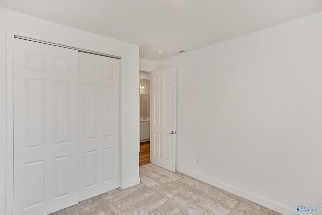 unfurnished bedroom featuring light colored carpet and a closet