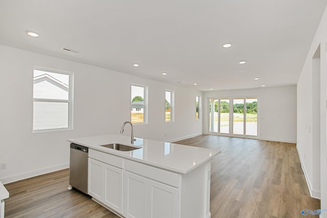 kitchen with sink, light hardwood / wood-style flooring, dishwasher, white cabinetry, and an island with sink