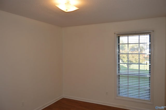 empty room with dark hardwood / wood-style floors and a textured ceiling