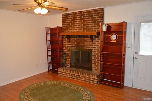 unfurnished living room with a fireplace, wood-type flooring, ceiling fan, and crown molding