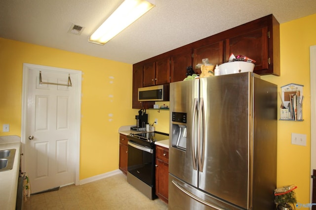 207 Brook Wind Dr, Hazel Green, AL 35750 - kitchen with appliances with stainless steel finishes, visible vents, light countertops, dark brown cabinets, and light floors
