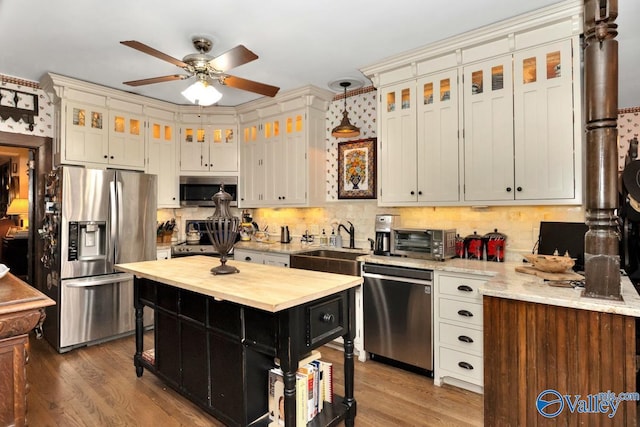 kitchen with sink, decorative light fixtures, stainless steel appliances, and hardwood / wood-style floors