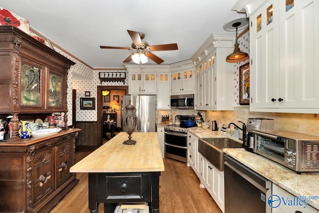 kitchen featuring wood counters, sink, appliances with stainless steel finishes, pendant lighting, and light hardwood / wood-style floors